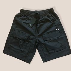 OAKLEY Enhance FGL UPF 50+ Cargo Shorts Black Size L  Elasticized drawstring waist - Pull-on style - Side seam pockets; back welt pocket - Front hook-and-loop flap pockets - UPF 50+ sun protection - Woven construction - Approx. 13" rise, 7" inseam (size M)  100% nylon Black Casual Cargo Pants With Built-in Shorts, Black Cargo Pants With Built-in Shorts For Outdoor, Outdoor Pants With Built-in Shorts, Outdoor Black Cargo Pants With Built-in Shorts, Short Outdoor Activity Pants With Side Pockets, Bottoms With Pockets For Summer Outdoor Activities, Short Outdoor Pants With Side Pockets, Functional Sports Shorts With Multiple Pockets, Utility Style Sports Bottoms With Built-in Shorts