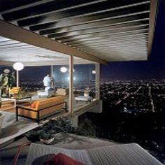 a living room filled with furniture next to a large window overlooking the city at night