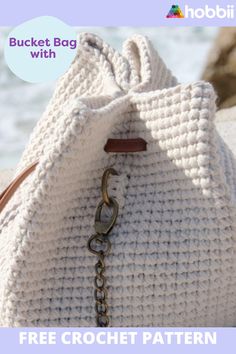 a crochet bag with a chain hanging from the front and side, on a beach