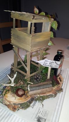 a small wooden structure sitting on top of a table next to a bottle of wine