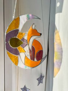 a stained glass sun catcher with a fox on the moon hanging from it's side