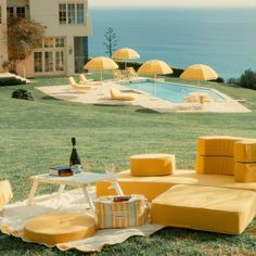 a yellow couch sitting on top of a lush green field next to a swimming pool