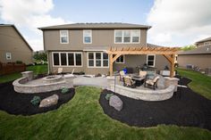 an outdoor patio with fire pit and seating area in the middle of it, surrounded by grass