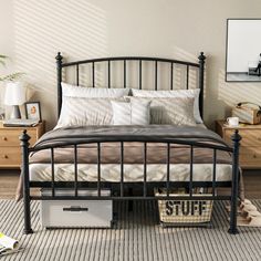 a black metal bed frame with white pillows and blankets on it in a bedroom setting