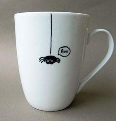 a white coffee cup with a spider on it's side and a bubble saying boo