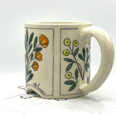 a coffee mug with flowers painted on the outside and inside is sitting on a doily