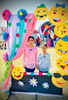 two people standing in front of a display with emoticions on it and decorations