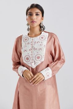 Dull pink straight tunic with a contrast hand embroidered panel on the yoke and cuffs. Component: 1 Pattern: Embroidery Type Of Work: Thread and Beads Neckline: Round Sleeve Type: Full Fabric: Silk Chanderi Color: Pink Other Details:  Cuffs with loop buttons Contrast panel on the yoke and cuffs Closure: Loop button front Note: Pant worn by the model is not for sale Disclaimer: Variations in fabric caused during the hand-weaving process  are not to be treated as defects. Occasion: Work - Aza Fash Designer Embroidered Neckline Kurta Tunic, Designer Embroidered Neckline Tunic Kurta, Festive Tunic Kurta With Embroidered Sleeves, Eid Long Sleeve Sets With Embroidered Neckline, Eid Sets With Embroidered Neckline And Long Sleeves, Festive Embroidered Sleeve Tunic Kurta, Long Sleeve Sets With Embroidered Neckline For Eid, Embroidered Sleeves Kaftan For Eid, Festive Tunic Kurta With Embroidered Neckline