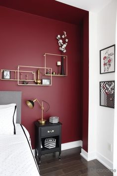 a bedroom with red walls and white bedding, black nightstands and pictures on the wall