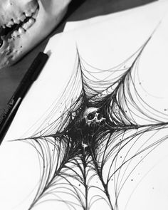 a drawing of a spider web on paper next to a pencil and crayon