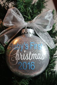 a baby's first christmas ornament hanging on a tree with a bow