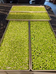 three trays filled with green peas sitting on top of a counter