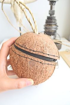 a person holding a coconut in front of a table with a lamp on top of it