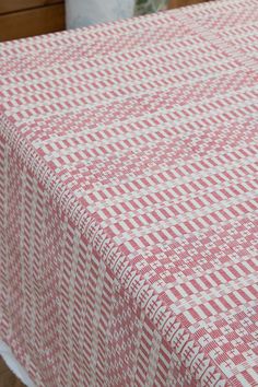 a red and white checkered table cloth on top of a wooden table with a vase in the background