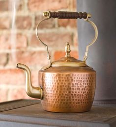 a copper tea kettle sitting on top of a stove