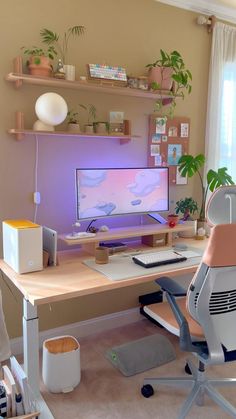 a desk with a computer on it in front of a window and potted plants