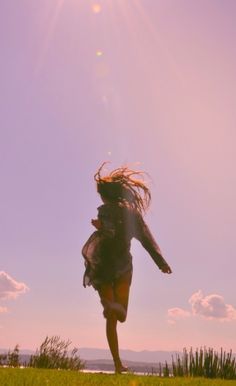 a woman is jumping in the air with her hair blowing