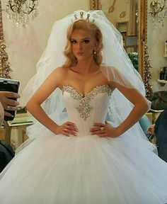 a woman in a white wedding dress is taking a selfie with her cell phone