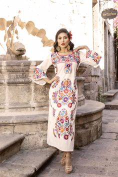 This Beautiful Mexican Floral Dress is the perfect dress for a special event or Mexican Fiesta.  It reflects the Mexican culture through its unique embroidered design and vibrant colors.  It has laces to tie on the back for an adjustable and comfortable fit.  It is embroidered by Artisanal Machine- hand manipulated by Mexican Artisans in Guanajuato, Mexico. It's made out of fresh Mexican Cotton and is full of embroidered multicolor flowers. Size S - XL Shop more Mexican Dresses here:  https://ww Traditional Dresses Mexican, Traditional Mexican Dress Wedding, Mexican Style Outfits, Mexican Fashion Modern, Mexican Dresses For Women, Mexican Theme Dresses, Mexican Dresses Traditional, Traditional Mexican Wedding Dress, Dress Latina