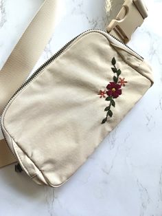 a cross body bag sitting on top of a white marble counter next to a camera