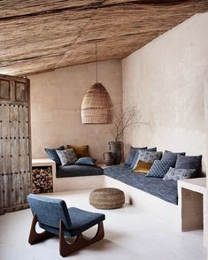 a living room filled with furniture and pillows on top of a white floor next to a wooden ceiling