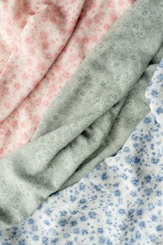 three different colored sheets laying next to each other on top of a bed with blue and pink flowers