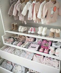 a white shelf filled with lots of baby clothes