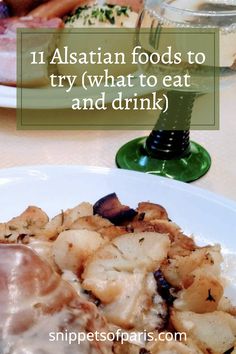 a white plate topped with meat and potatoes next to a glass of water on a table