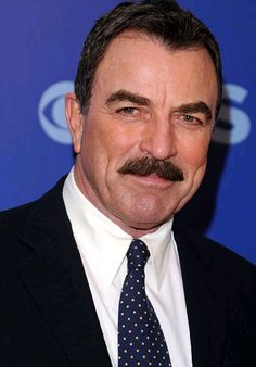 a man wearing a suit and tie with a mustache