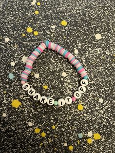 a beaded bracelet with the word shame written on it and confetti sprinkles scattered around