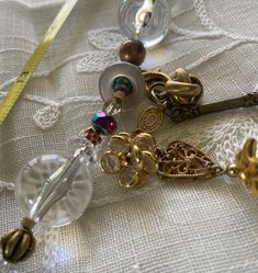 a close up of beads and other items on a white table cloth with a measuring tape in the background