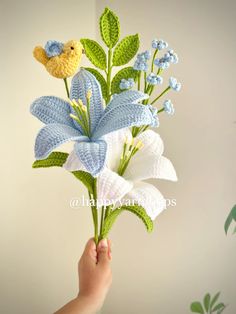 a hand holding a bouquet of flowers with a stuffed bird on top