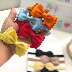 a hand holding several small bows in different colors and sizes on it's fingers