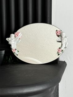 a mirror sitting on top of a black table next to a potted plant with pink flowers