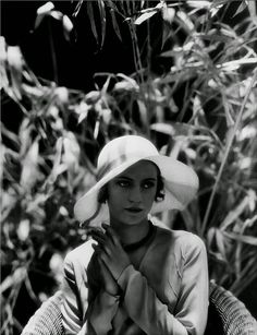 black and white photograph of a woman wearing a hat with her hands clasped in front of her face