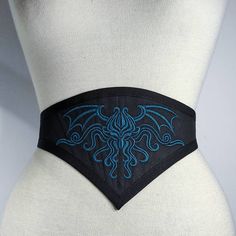 Gothic waist belt made with black cotton, finished with black cotton canneté. An elegant representation of Cthulhu Is embroidered with a teal thread. Adjustable with elastic band and metallic regulators. Light boned with syntethic whalebones. Can be worn alone, on dresses, on jackets or on corsets, as you wish! 🌹*SIZE* 🌹 I'll set the elastic band to fit your personal size, please send me your waist measure when you purchase It . Please feel free to ask me, if you have questions. -------------- Black Steampunk Corset Belt For Larp, Black Steampunk Corset Belt For Halloween, Black Fitted Corset Belt For Festivals, Fitted Black Corset Belt For Festival, Black Steampunk Corset Belt For Festival, Gothic Black Corset Belt For Larp, Punk Black Corset Belt For Halloween, Black Gothic Corset Belt For Larp, Gothic Black Corset Belt For Costume Party