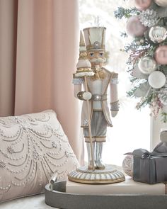 a nutcracker figurine sitting on top of a table next to a christmas tree