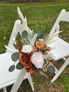 an arrangement of flowers is sitting on a white folding chair in the middle of a grassy field