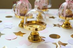 there are three glass bell jars on the table with confetti around it and gold foil stars