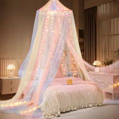 a white bed with a pink canopy and lights on the top, in a bedroom