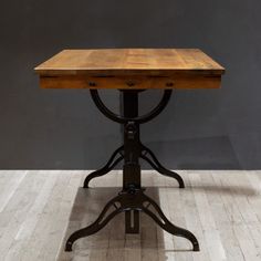 a wooden table sitting on top of a hard wood floor next to a gray wall