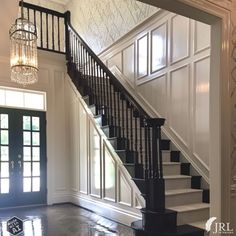 the stairs in this house are black and white with glass chandelier above them