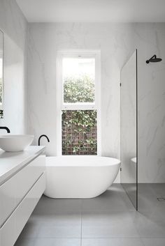 a white bathtub sitting next to a window in a bathroom