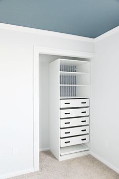 an empty closet with white drawers and blue ceiling