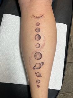 a person with a tattoo on their leg that has planets and sun in the middle