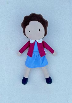 a small doll with brown hair and blue dress