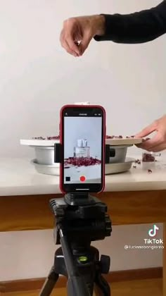 a person is taking food out of a bowl on a tripod with their cell phone