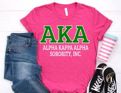 a pink shirt that says akaa with green letters on the front and white letters on the back