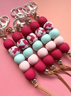 several different colored beads are attached to a keychain on a pink and white background