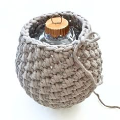 a small crocheted basket with a candle in the middle and a cord attached to it